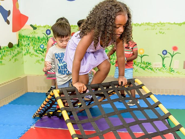 Children climbing on a Freedom Climber in a bright playroom